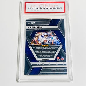 May include: A Michael Irvin Dallas Cowboys football card, graded and encased in a protective holder. The card features a photo of Irvin in his Cowboys uniform and details his achievements. The card is from the 2025 Panini Mosaic Football series.