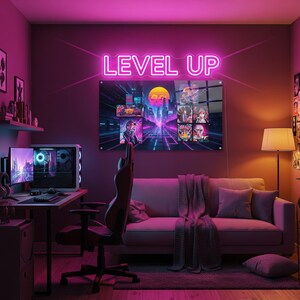 May include: A neon sign that reads "LEVEL UP" above a gaming setup. The room is lit with pink and purple hues, featuring a computer, gaming chair, and a couch. A large framed artwork with retro gaming graphics hangs on the wall.