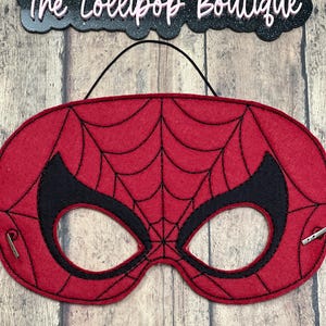 May include: Red felt Spiderman mask with black webbing and eye holes. The mask has a black elastic strap for wearing.