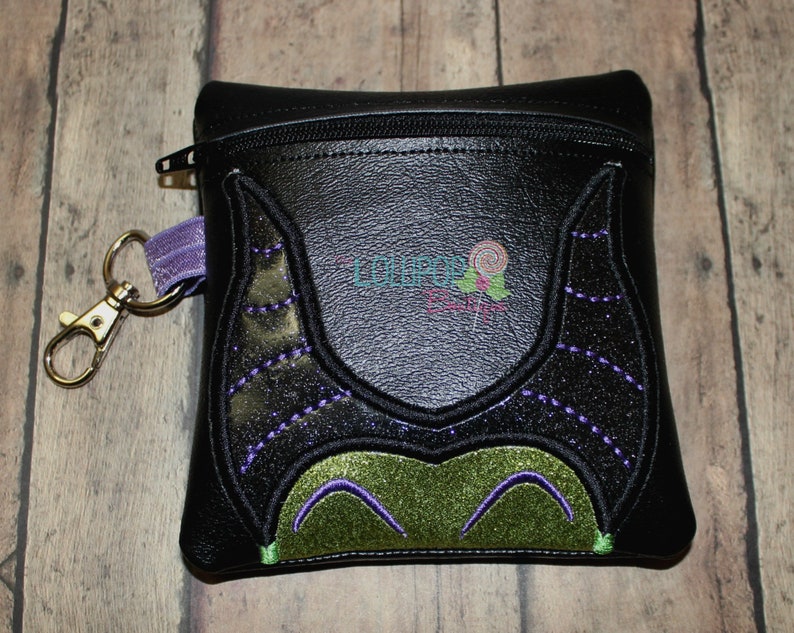 May include: Black zippered pouch with a green and purple embroidered design of Maleficent's horns and face.