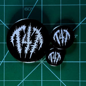 May include: Three black and white button pins with the word "FAITH" in a stylized font.