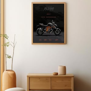 May include: A framed poster featuring a black and orange KTM 1290 Superduke motorcycle on a black background. The poster includes the text "KTM RACING 2017 1290 SUPERDUKE".