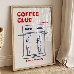 Könnte beinhalten: Ein gerahmter Kunstdruck mit Kaffeemotiv. Der Druck zeigt die roten Worte "COFFEE CLUB" mit "Served Daily" über einer blauen Illustration einer Kaffeemaschine. Unter der Maschine blicken zwei Figuren nach oben, und die Worte "Every Morning" sind rot.