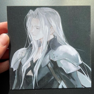 May include: A square art print featuring a side profile of a character with long, flowing silver hair. The character wears a black outfit with silver shoulder armor. The artwork is set against a dark background.