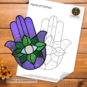 May include: A stained glass Hamsa hand in shades of purple, green, and blue, with an eye design at the center. A pattern for the Hamsa hand is on a white sheet of paper. The words "Hand of Hamsa" are at the top of the paper.