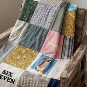 Op de afbeelding: Een patchwork deken gemaakt van diverse stoffen vierkanten met uiteenlopende patronen zoals paisley, bloemen, ruiten en strepen. Eén vierkant toont een hondenportret, een ander de tekst "PALM SPRINGS" en een ander de tekst "SIX EVEN."