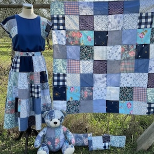 Pode incluir: Um conjunto de patchwork com uma blusa e saia azuis, um edredom, um urso de pel&uacute;cia e duas bolsas com z&iacute;per. Os itens s&atilde;o feitos de v&aacute;rios tecidos azuis com estampas florais, xadrez e lisas. O edredom &eacute; exibido atr&aacute;s dos outros itens.