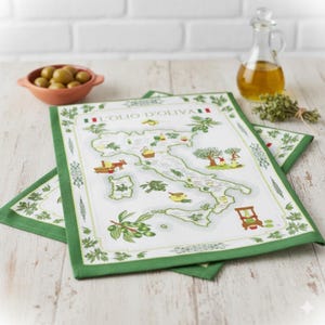 Puede incluir: Dos paños de cocina blancos y verdes con temática italiana. Los paños presentan un mapa de Italia con ilustraciones de ramas de olivo, aceite de oliva y otros elementos italianos. El texto "L'OLIO D'OLIVA" está impreso.