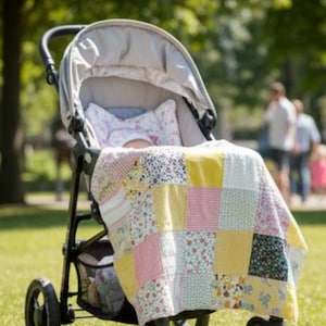 Pode incluir: Um bebê em um carrinho de bebê está coberto com um edredom de retalhos. O edredom apresenta quadrados de tecidos florais, xadrez e lisos em tons de rosa, amarelo e branco. O carrinho tem uma capota cinza e uma estrutura preta.