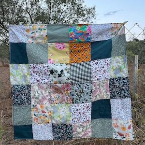 Può includere: Una trapunta patchwork con una varietà di motivi floreali e geometrici in tonalità di verde, giallo, bianco e rosa.