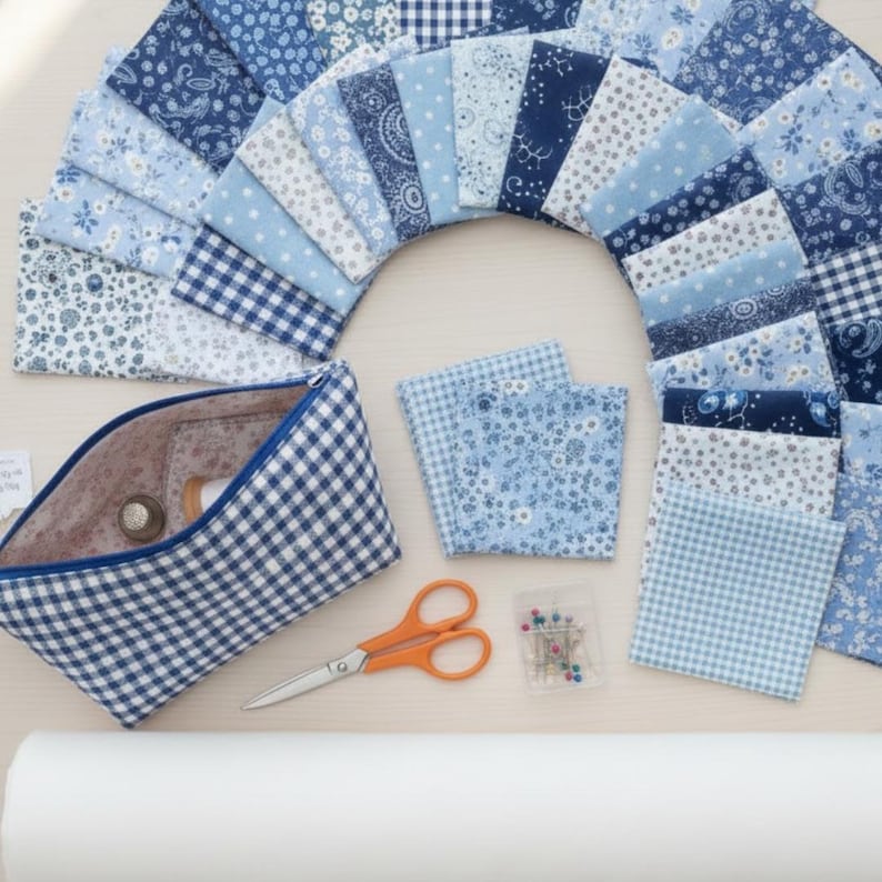 Pode incluir: Uma cole&ccedil;&atilde;o de quadrados de tecido azul em v&aacute;rios padr&otilde;es, dispostos em arco. Uma bolsa com z&iacute;per xadrez, tesouras laranja, alfinetes e um rolo de tecido branco sugerem um tema de costura ou colchas.