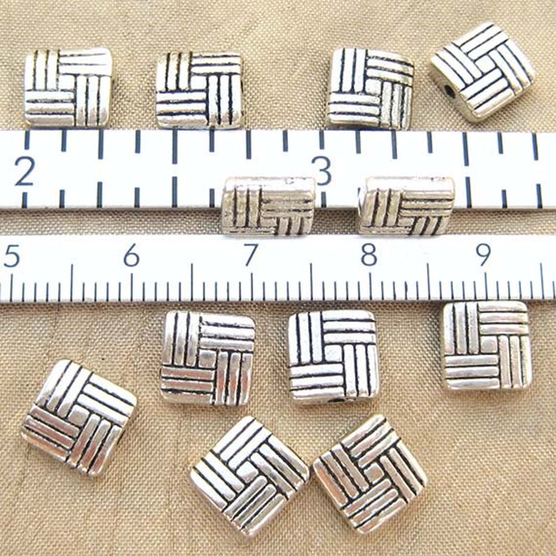 8 millimeter puff square beads with a basketweave design with standard and metric ruler for scale