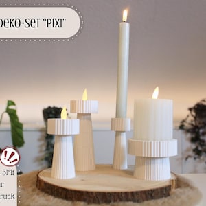 Könnte beinhalten: Ein weißes Kerzenset mit verschiedenen Formen und Größen, darunter eine hohe, dünne Kerze und mehrere kürzere, breitere Kerzen. Die Kerzen stehen auf einem Holzsockel. Der Text "DEKO-SET 'PIXI'" befindet sich oben im Bild.