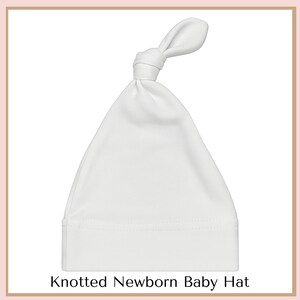 A white newborn baby hat with a knotted bow at the top.