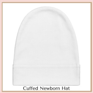 A white, cuffed newborn hat is shown against a white background.
