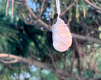 May include: A delicate silver chain necklace with a light brown, irregularly shaped stone wrapped in silver wire.