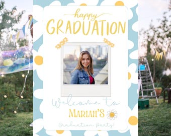 Könnte beinhalten: Ein Schild für eine Abschlussfeier mit einem hellblauen Gänseblümchenmuster im Hintergrund. Das Schild zeigt ein Foto einer Frau, die Worte "happy GRADUATION" und "Welcome to Mariah's Graduation party!" in Gelb und Hellblau.