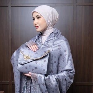 May include: A light grey satin handbag with a gold chain strap and a decorative gold clasp. The bag is part of a matching set with a floral patterned shawl and head covering.