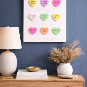 May include: A set of three ceramic mugs with a speckled, cream-colored glaze. Each mug features a different hand-painted design: a blue and green leaf, a yellow and orange flower, and a red and pink berry. The mugs have a simple, rounded shape.