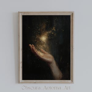 以下が含まれることがあります： 暗い背景に手を伸ばし、金色の光が爆発している。光は、小さなキラキラ光る粒子でできているように見える。