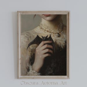 May include: A framed painting depicting a woman in a white lace dress holding a small bat in her hand. The woman is wearing a gold necklace with a pendant. The painting is set against a white background.