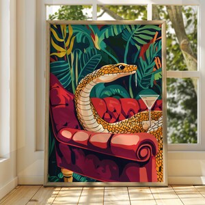 Puede incluir: Una serpiente amarilla con una copa de martini se sienta en un sillón rojo en un entorno de jungla. La serpiente está enroscada en la silla con la cabeza apoyada en el reposabrazos. La copa de martini está en el reposabrazos junto a la cabeza de la serpiente. El fondo es una jungla exuberante con hojas y enredaderas verdes.