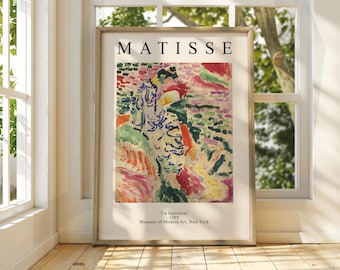 May include: A framed print of a painting by Henri Matisse titled "La Japonaise" from 1905. The painting depicts a woman in a colorful, abstract style with a background of pink, green, and yellow hues. The print is from the Museum of Modern Art in New York.