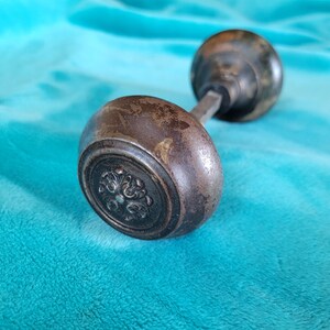 May include: A vintage door knob with a decorative design. The knob is made of metal and has a dark brown finish.