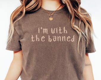 May include: A brown t-shirt with the text "I'm with the banned" printed in a gothic font.