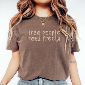 May include: A brown t-shirt with the text "free people read freely" in a gothic font.