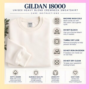 May include: A cream-colored Gildan 18000 heavy blend crewneck sweatshirt with a visible brand label. The image includes text detailing care instructions such as machine wash cold, do not bleach, tumble dry low, do not iron on design, and do not dry clean.