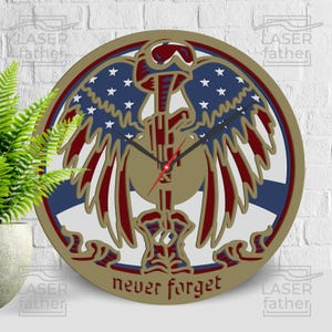 May include: A round wooden clock with a patriotic design. The clock features a central emblem with a helmet, rifle, and wings, incorporating the colors of the American flag. The words "never forget" are at the bottom. The clock hands are black with a red second hand.