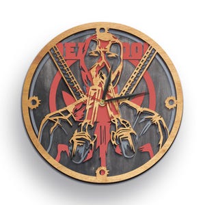 May include: A round wooden clock with a black and gray wood grain finish. The clock face features a red and black silhouette of Deadpool holding two guns. The clock hands are black and red. The clock is 12 inches in diameter.