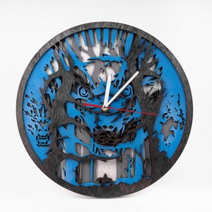 May include: A blue and black wooden wall clock with a laser cut design of a wolf's face. The clock has white hands and a red second hand.