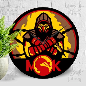 May include: A black and yellow round clock with a red and yellow dragon logo and the text "MOK" in the center. The clock features a black silhouette of a character from the Mortal Kombat video game series with a red and yellow color scheme.