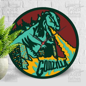 Op de afbeelding: Een ronde houten klok met een groen en geel Godzilla-ontwerp. De klok heeft een rood en zwart wijzerplaat met het woord "Godzilla" in groen en geel.
