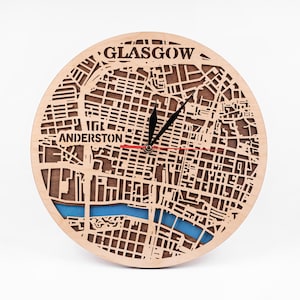 May include: A circular wooden clock, laser-cut with a map of Glasgow. The clock face includes the names "Glasgow" and "Anderston". The hands are black, with a red second hand. A blue river feature is visible. The clock is made of wood.