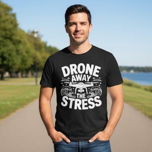 May include: Black t-shirt with the white text "DRONE AWAY THE STRESS" and a drone graphic. The design includes waves and clouds. The shirt is short-sleeved and made of a soft material.