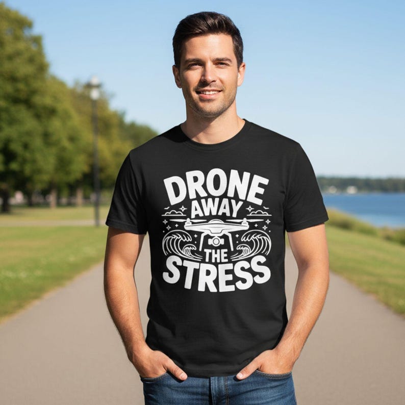 May include: Black t-shirt with the white text "DRONE AWAY THE STRESS" and a drone graphic. The design includes waves and clouds. The shirt is short-sleeved and made of a soft material.