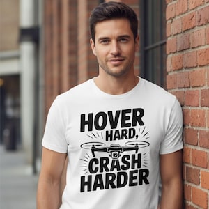 May include: White t-shirt with the text "HOVER HARD, CRASH HARDER" in black, along with a drone graphic. The shirt is made of a soft material.