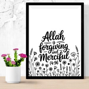 May include: A framed black and white print with the words "Allah is Forgiving and Merciful (4:96)". The print features floral illustrations at the bottom. A small white vase with pink flowers sits to the left of the frame.