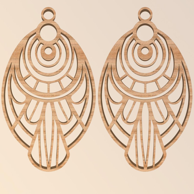 May include: Two wooden earrings with an intricate, openwork design. Each earring is an elongated oval shape with a series of concentric circles and geometric patterns. The earrings are a light brown color and have a small loop at the top for hanging.
