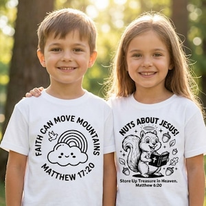 May include: Two children wearing white t-shirts with black graphic designs. One shirt says "Faith Can Move Mountains" with a rainbow and cloud. The other says "Nuts About Jesus!" with a squirrel holding a book. Both shirts have Bible verses.