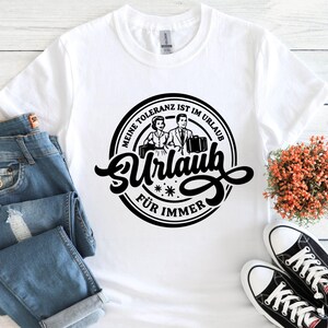 May include: White t-shirt with a black graphic. The graphic features a vintage illustration of a couple with luggage, and the German text "Meine Toleranz ist im Urlaub f&uuml;r immer."