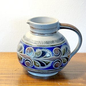 May include: A set of three ceramic mugs with a speckled, matte finish. The mugs are in shades of cream, light gray, and dark gray. Each mug has a simple, minimalist design and a rounded handle. Perfect for coffee or tea.