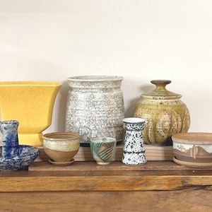 May include: A selection of ceramic pottery items, such as vases, bowls, and jars, in diverse forms and dimensions. The colour scheme features yellow, white, brown, blue, and green. The pottery exhibits textured surfaces and decorative designs.