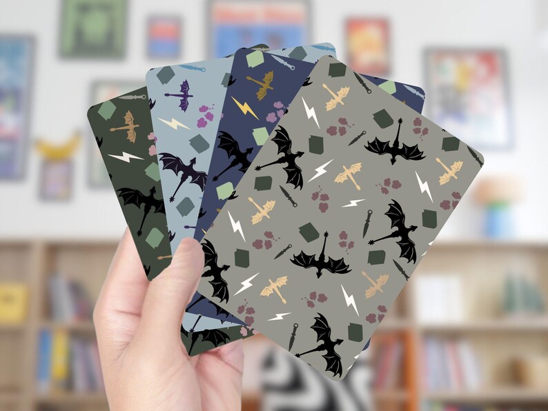 Op de afbeelding: Een hand houdt een waaier van speelkaarten met een herhalend patroon van zwarte draken, bliksemschichten, zwaarden en andere fantasie-elementen. De kaarten hebben een verscheidenheid aan achtergrondkleuren, waaronder groen, blauw en grijs.