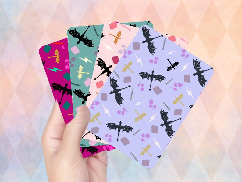 May include: A hand holds four rectangular cards with dragon and fantasy-themed patterns. The cards feature black dragons, swords, lightning bolts, and other fantasy elements on backgrounds of pink, teal, purple, and magenta.