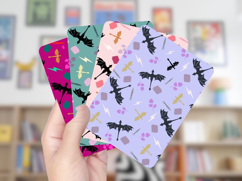 May include: A hand holds a fan of colorful cards with dragon and fantasy-themed patterns. Each card features a different background color: fuchsia, teal, pink, and lavender. The patterns include black dragons, swords, lightning bolts, and other fantasy elements.