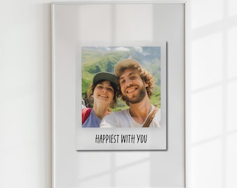 May include: A framed photo of a couple smiling at the camera. The photo is in a white frame and has a white background. The couple is standing in front of a green mountain range. The text "Happiest with you" is printed below the photo.